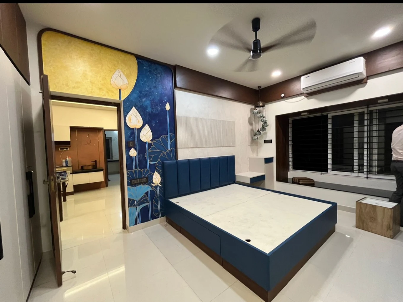 Master bedroom with blue upholstered bed and lotus mural
